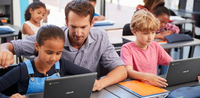 Teacher helping young students using laptops in class; Shutterstock ID 735954493; purchase_order: -; job: -; client: -; other: -
